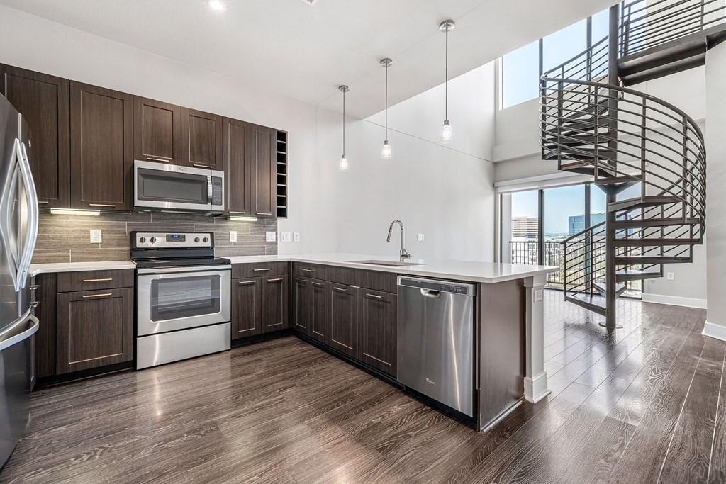 a kitchen with wooden cabinets and stainless steel appliances and a spiral staircase
