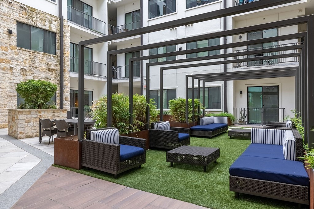 an outdoor patio with lounge furniture and tables in an apartment building
