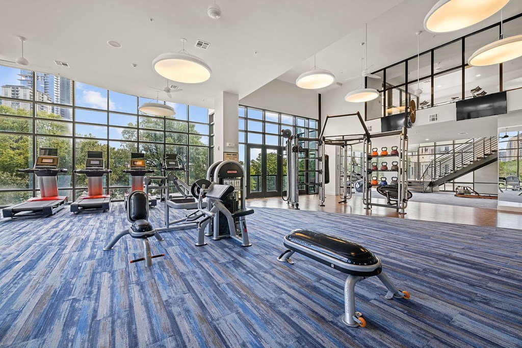 a workout room with weights and cardio equipment and large windows
