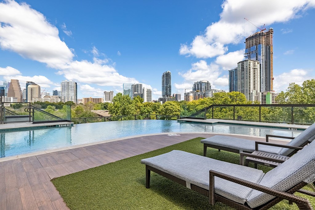 an outdoor pool with a city skyline in the background