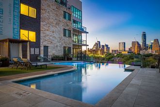 an apartment pool with a city skyline in the background