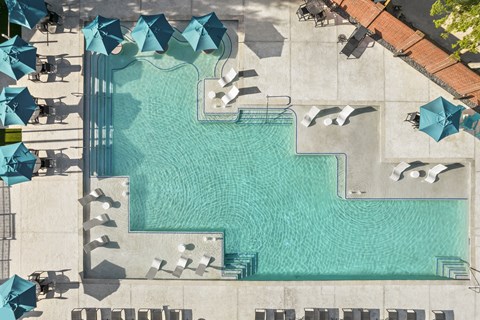 A large swimming pool surrounded by lounge chairs and umbrellas.