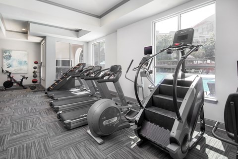 A gym with treadmills, elliptical machines, and a stationary bike.