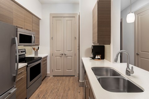 A modern kitchen with a stainless steel sink and wooden cabinets.