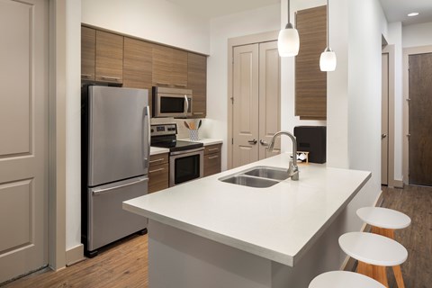 A modern kitchen with a white countertop and stainless steel appliances.