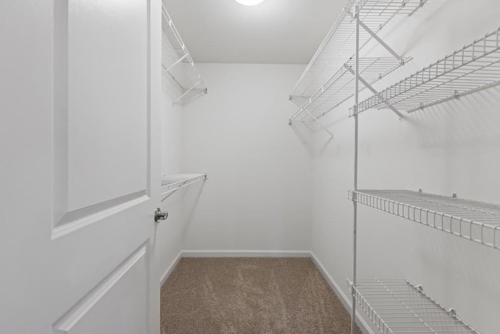 a walk in closet with white walls and shelves and a mirrored closet door