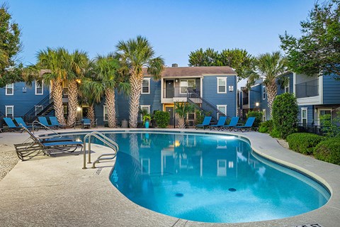 a swimming pool with palm trees in front of apartment buildings