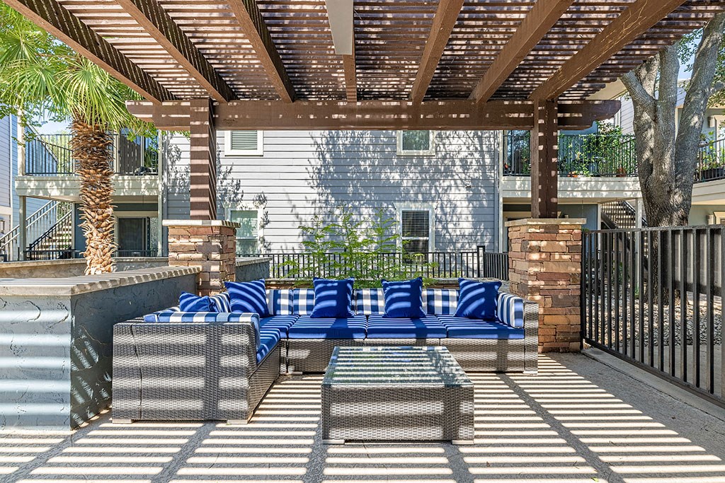 a covered patio with blue couches and tables