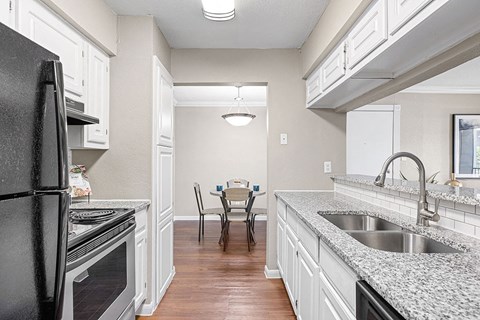 A kitchen with a black refrigerator and white cabinets.
