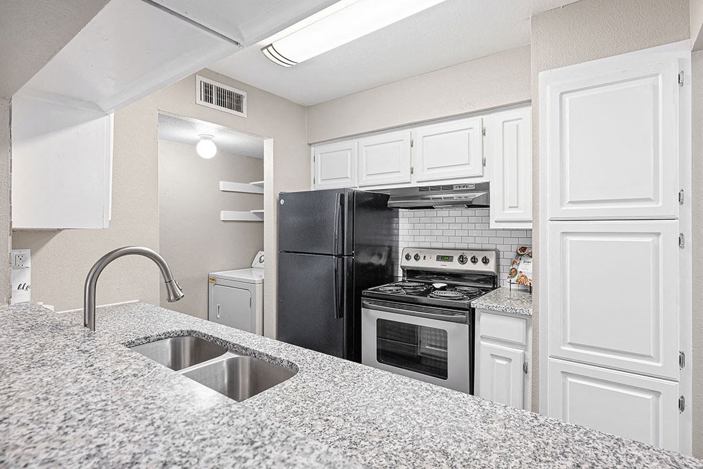 a kitchen with a sink and a black refrigerator