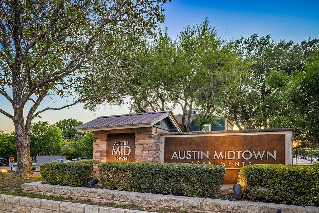 a sign apartments in front of trees