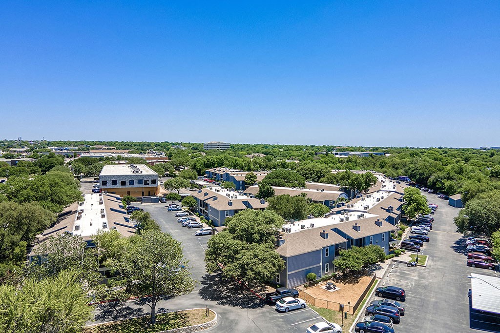 an aerial view of a parking lot with houses and trees