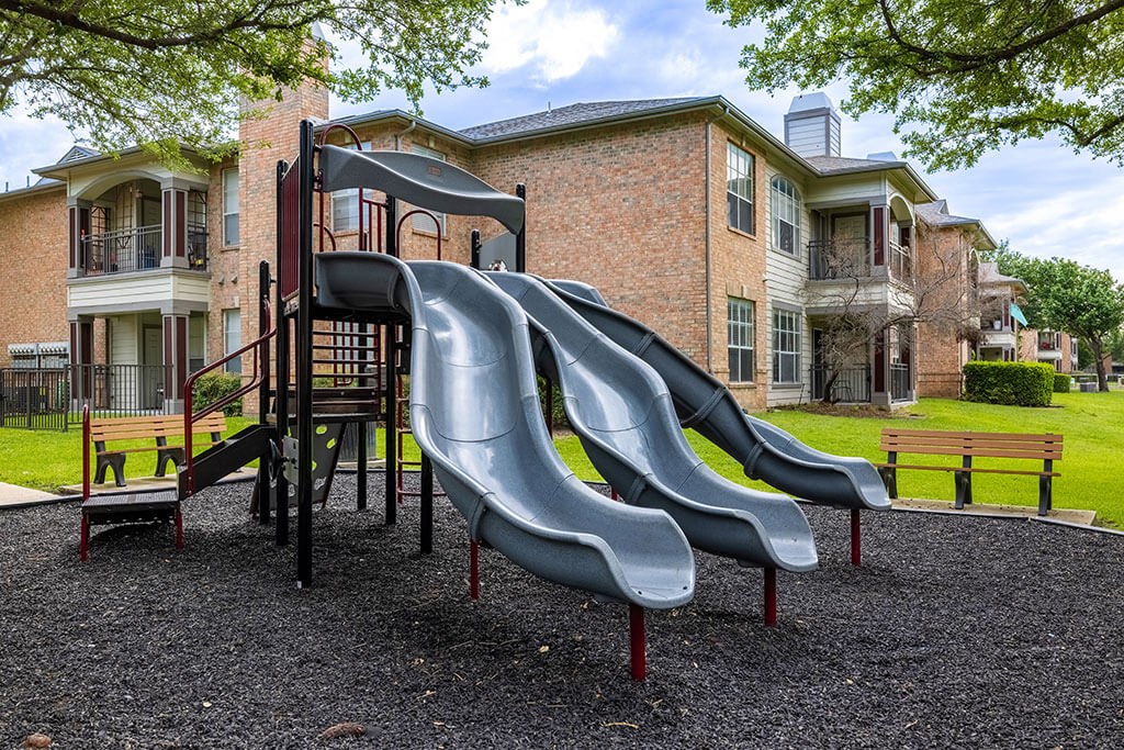 a playground with a slide in front of an apartment building