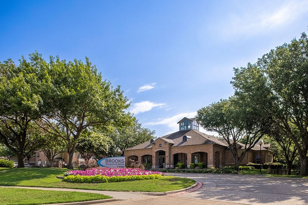 the front of a building with trees and flowers