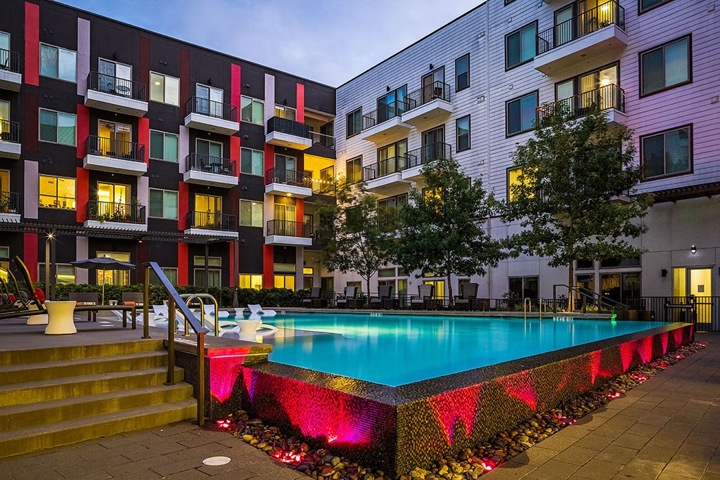 a swimming pool at night in front of an apartment building