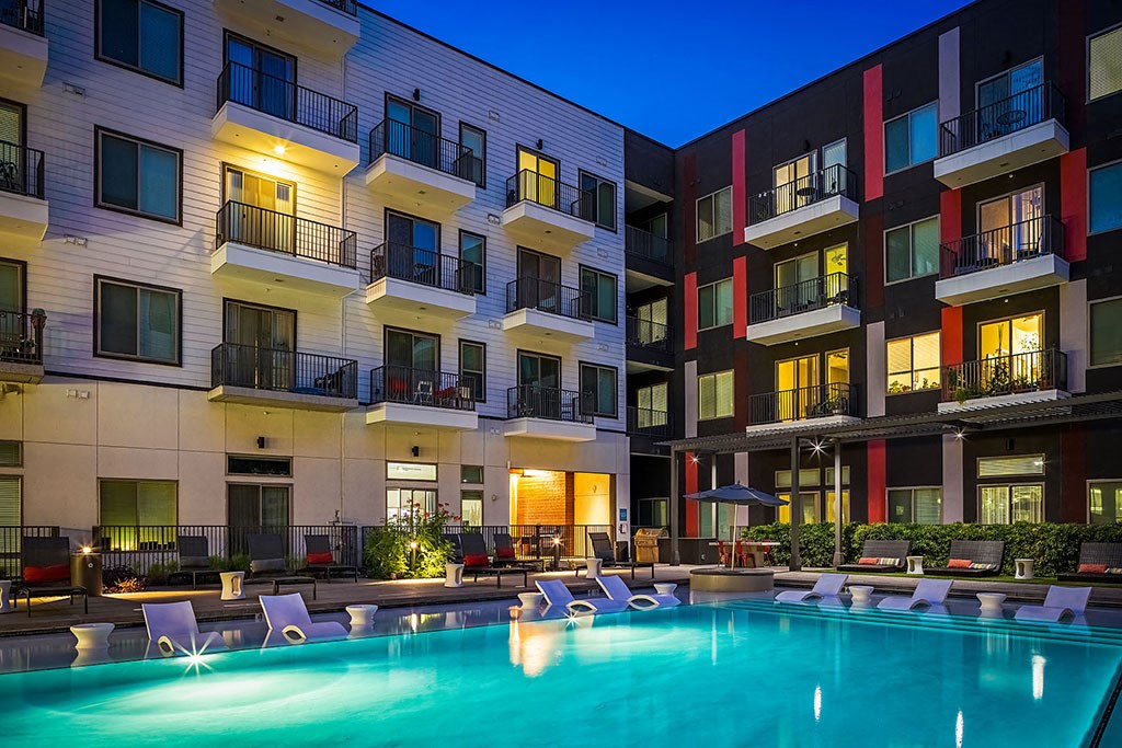 a swimming pool at night in front of an apartment building