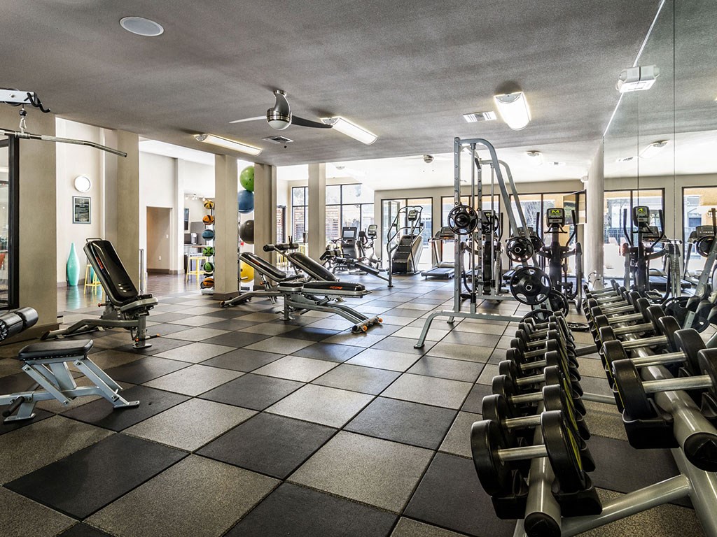 a gym with cardio equipment and weights on a tiled floor