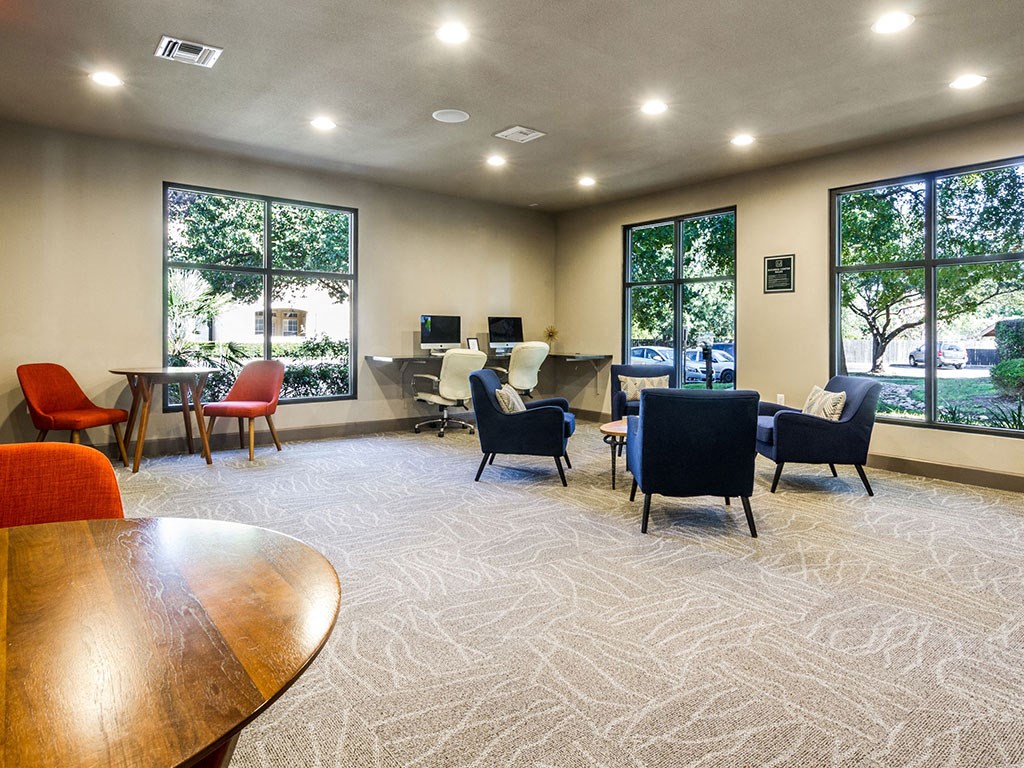 a lounge area with chairs and tables and large windows