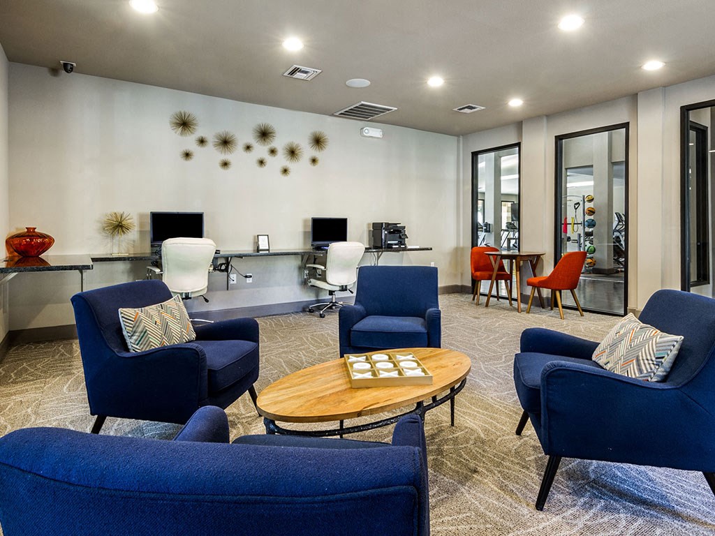 a lounge area with blue chairs and a coffee table