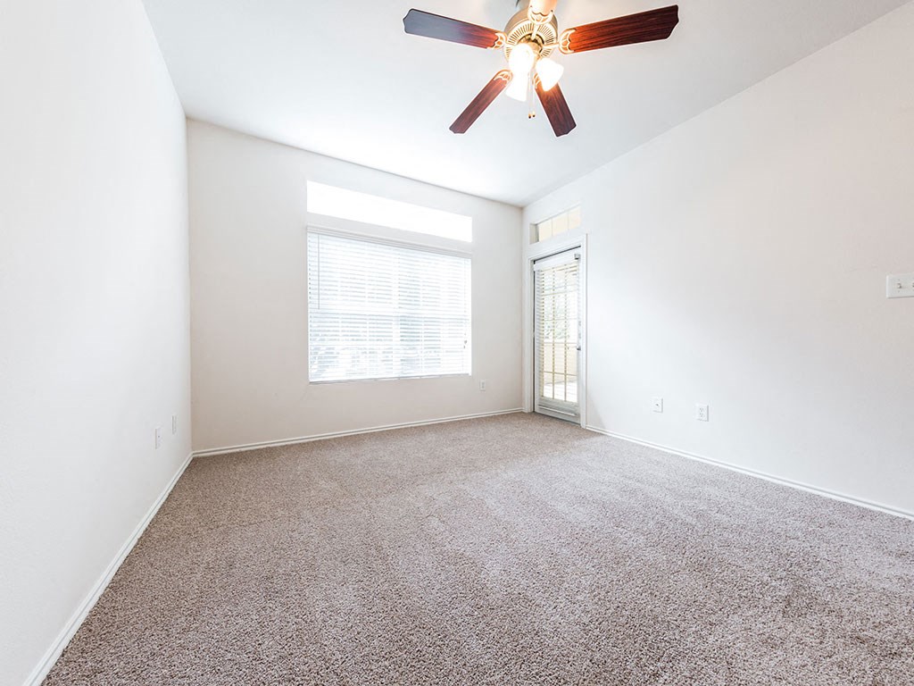 an empty living room with a ceiling fan and a window
