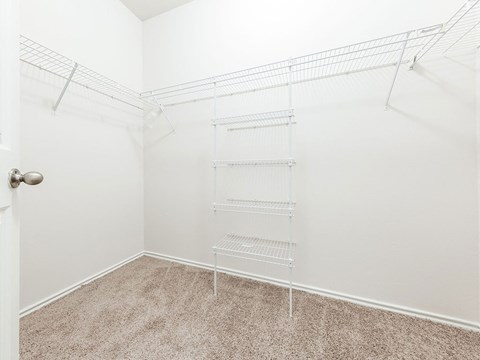 a spacious closet in a bedroom with white walls and carpet