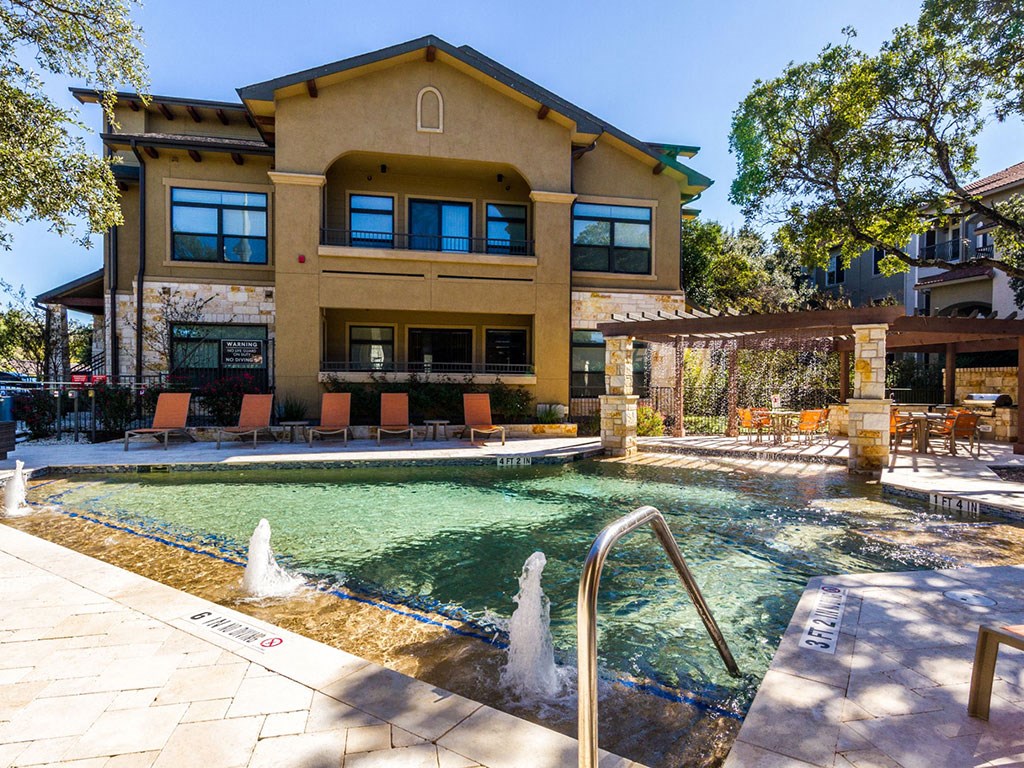 a pool is in front of a large house with a swimming pool