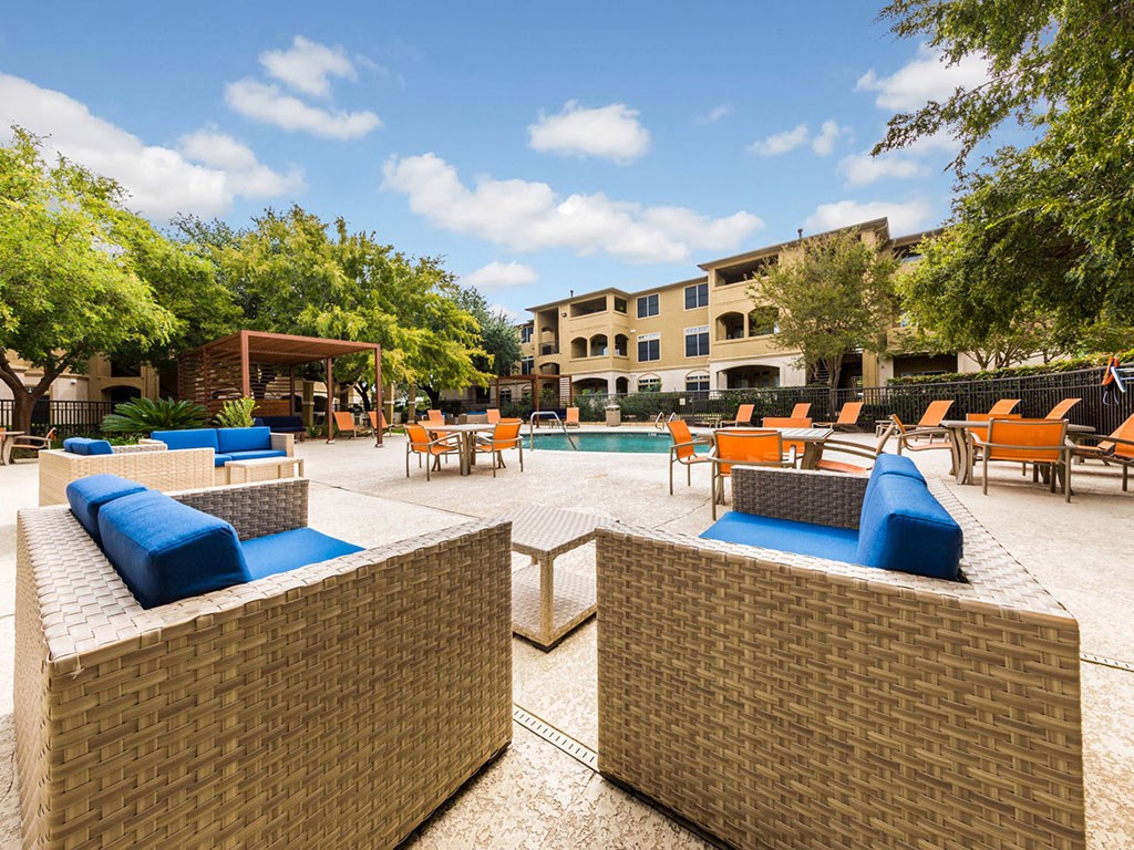 a pool with lounge chairs and tables in a courtyard