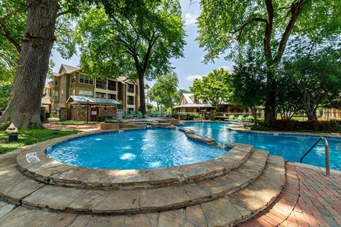 a large swimming pool with trees and buildings in the background