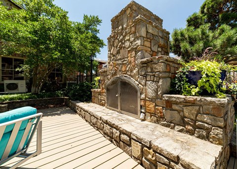 a backyard with a stone fireplace and a deck with a deck chair