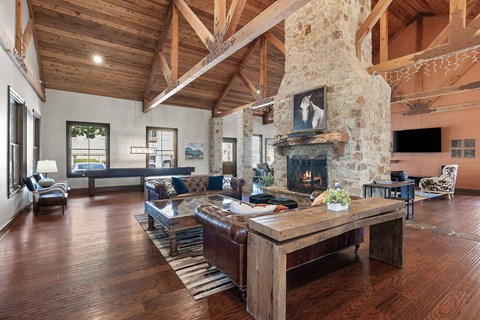 A large room with a stone fireplace and wooden floors.
