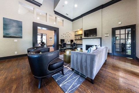 A black leather chair sits in a living room with a grey couch and a fireplace.
