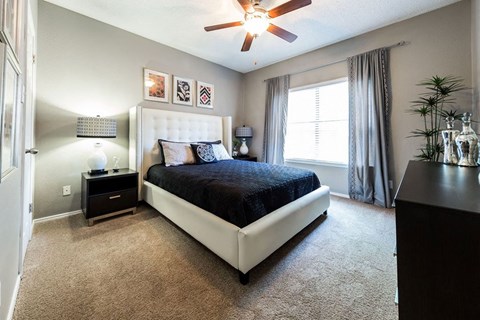 A bedroom with a large bed and a ceiling fan.