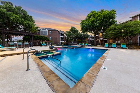 A swimming pool surrounded by trees and a building in the background.