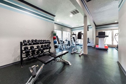 A gym with a variety of equipment including dumbbells and weight machines.