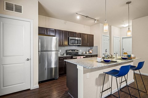 A kitchen with a white counter top and blue chairs.