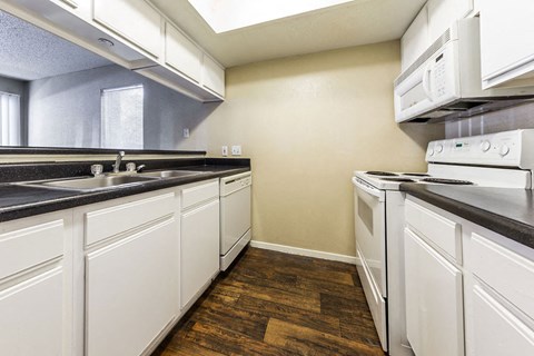 A kitchen with white cabinets and a black counter top.