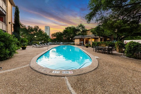 A round swimming pool surrounded by a gravel area with a sign that says "NO DIVING".