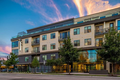 A modern multi-story building with a glass entrance and balconies.