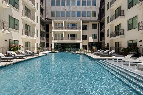 A large indoor swimming pool with lounge chairs on the side.