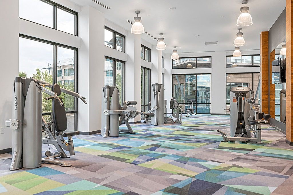 a gym with cardio machines and windows in a building