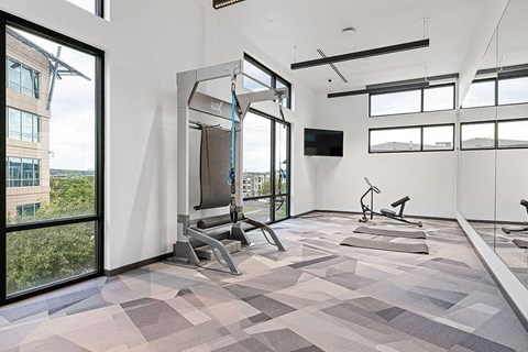 a workout room with windows and a view of the city