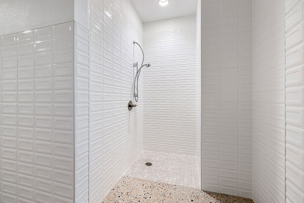 a white bathroom with a shower and a tiled wall