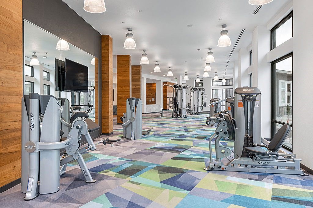 a gym with cardio machines and a tv