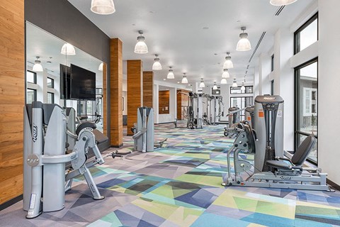 a gym with cardio machines and a tv