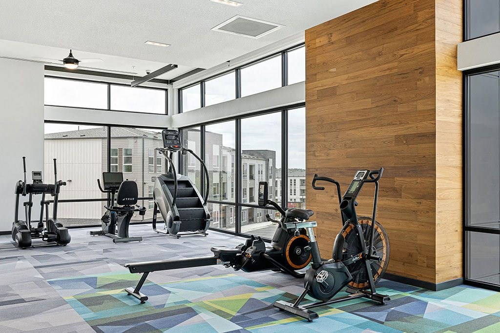 a workout room with treadmills and weights in a building with large windows