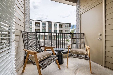 a balcony with two chairs and a table and a door