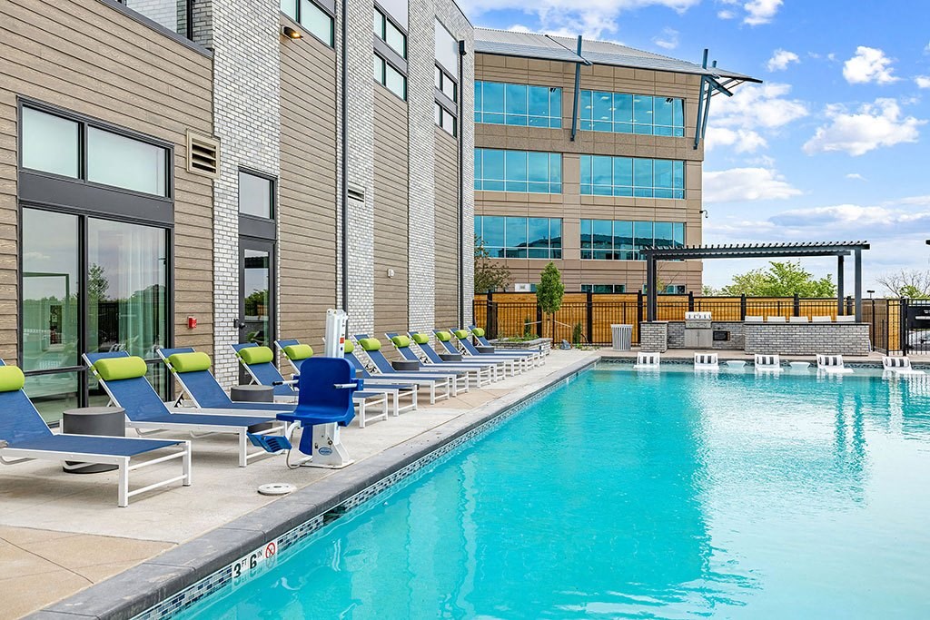 a swimming pool with blue and green chairs next to a building