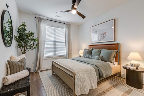 A bedroom with a large bed and a ceiling fan. at The Grayson, Fort Worth, TX