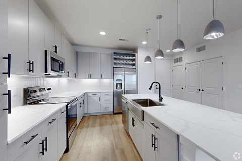 A modern kitchen with white cabinets and a wooden floor.