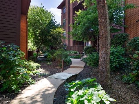 a walkway through a garden next to a building